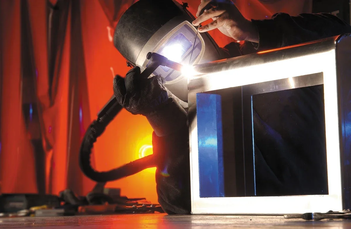 Sign fabrication — a welder working on an aluminium sign frame in Brand Consortia's workshop